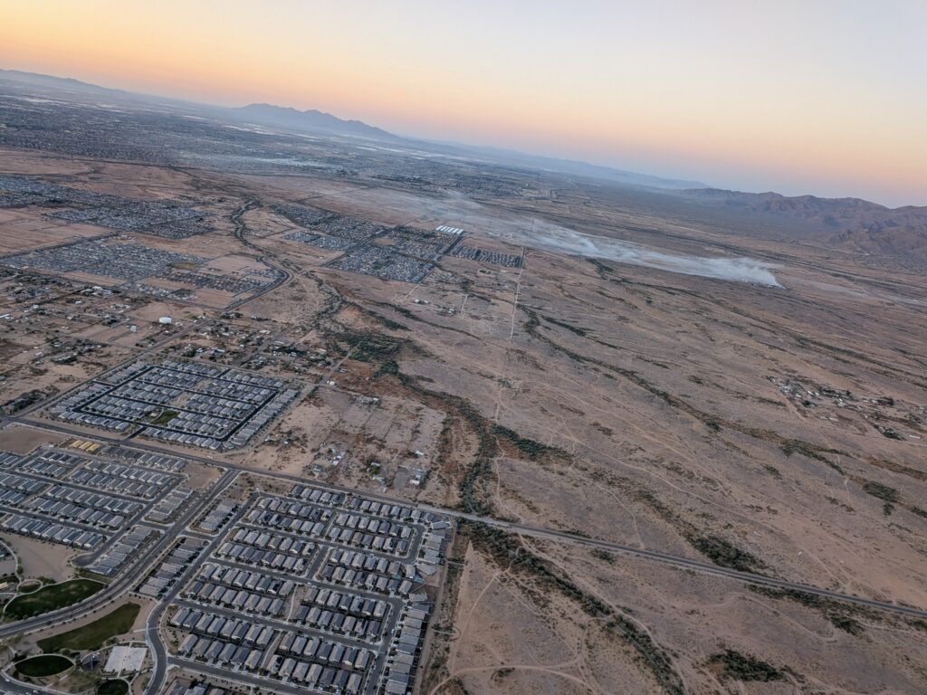 Aerial view from the BOTA balloon showing a long plume of smoke rising from the West Valley desert during the April 28, 2026 flight.