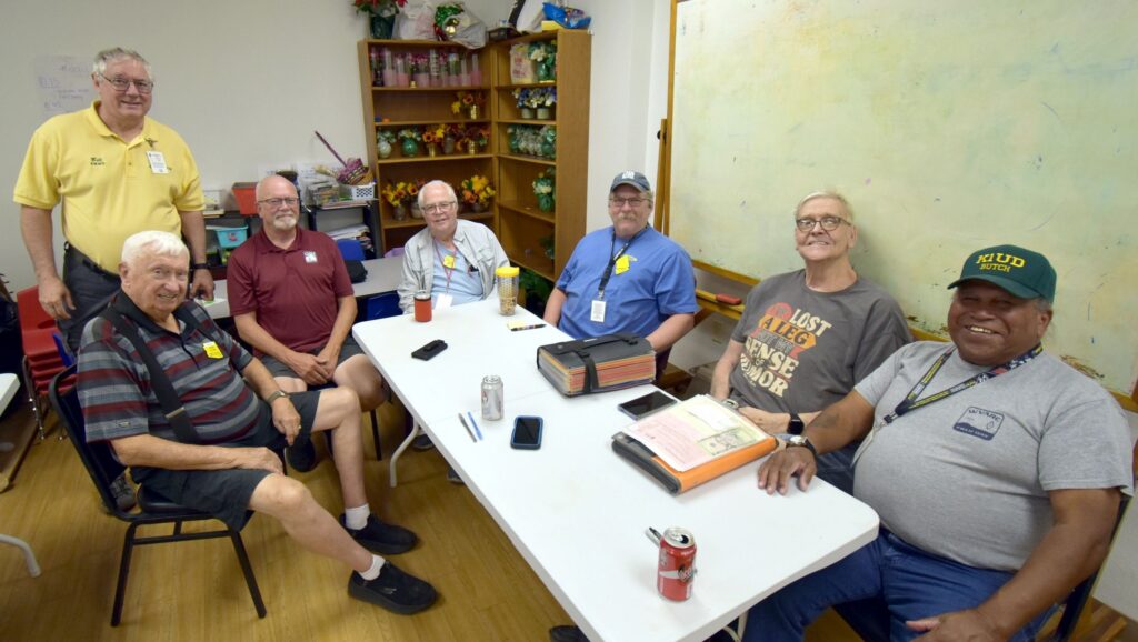 Seven West Valley Amateur Radio Club volunteer examiners gathered around a table at a license testing session.